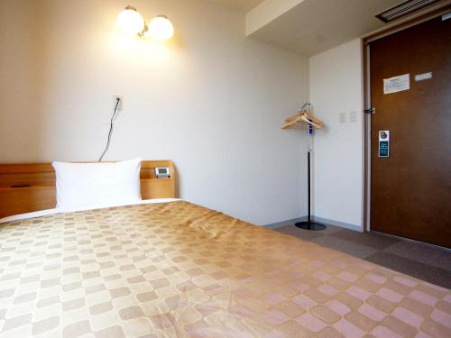 a bedroom with a bed and a door and a lamp at Hotel Trend Iwakuni in Iwakuni