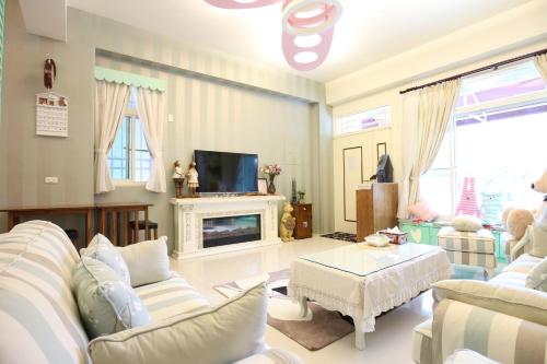 a living room with white furniture and a tv at Aunt's Bed and Breakfast in Taitung City