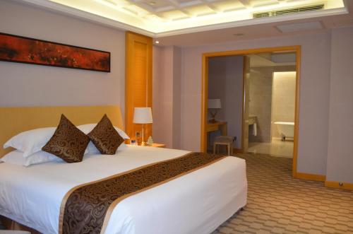 a bedroom with a large white bed and a bathroom at Hui Fu Jinling Hotel in Gaoyou