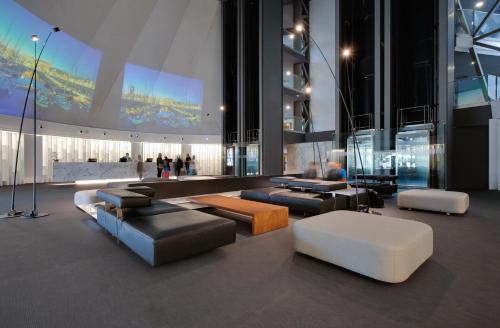 a lobby with couches and tables in a building at BAH Barcelona Airport Hotel in El Prat de Llobregat