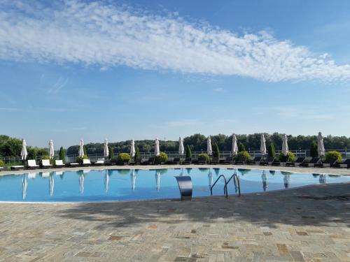 a swimming pool with chairs and a blue sky at Prestige Hotel in Belene