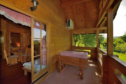 a porch of a wooden cabin with a table at Apartments Zafran in Smoljanac