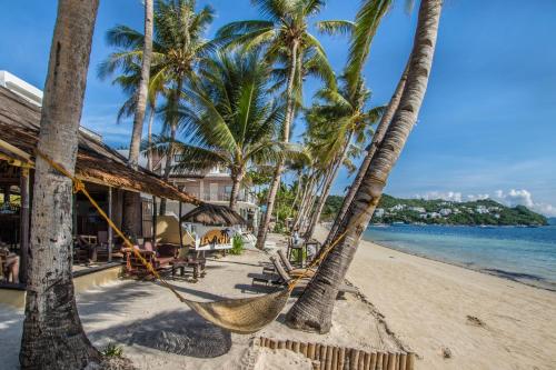 a hammock on a beach with palm trees at Levantin Boracay in Boracay