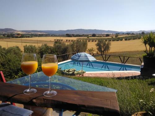 two glasses of orange juice sitting on a table next to a pool at Almatoscana in Campagnatico