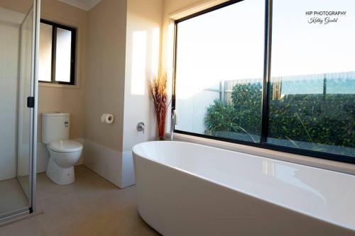 ein Badezimmer mit Badewanne und Toilette und einem Fenster in der Unterkunft Still Earth in Port Pirie