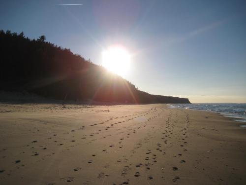a beach with footprints in the sand and the sun at Wisełka PERŁA Bałtyku in Wisełka
