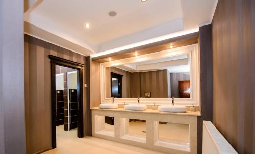 łazienka z 3 umywalkami i dużym lustrem w obiekcie Grand Hotel Sofianu w mieście Râmnicu Vâlcea