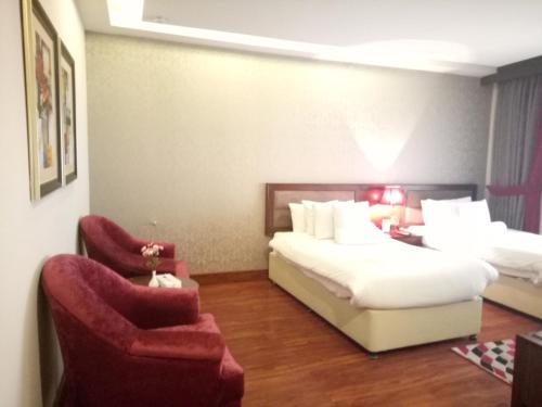a hotel room with a bed and two chairs at S Chalet Islamabad in Islamabad