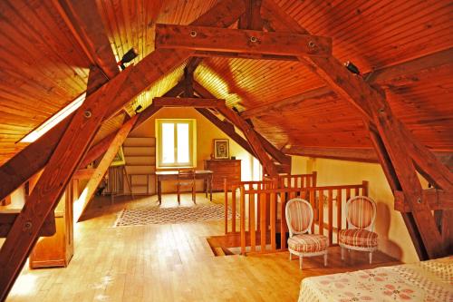 Cette chambre mansardée est dotée de poutres apparentes, d'un lit et de chaises. dans l'établissement Sabatou, le cottage Cévenol, à Florac Trois Riviere