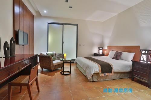 a bedroom with a bed and a table and a chair at Green Life Spa Hot Spring Hotel in Jiaoxi