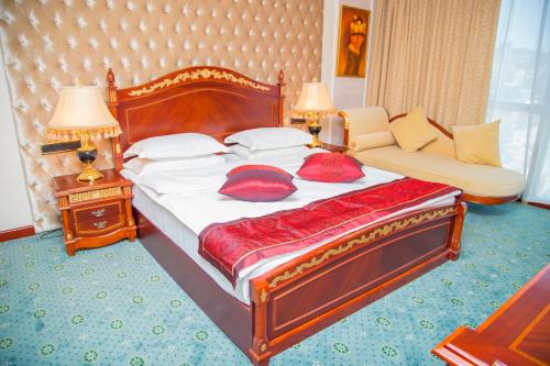 a bedroom with a bed with red pillows and a couch at Golden Coast Hotel in Baku