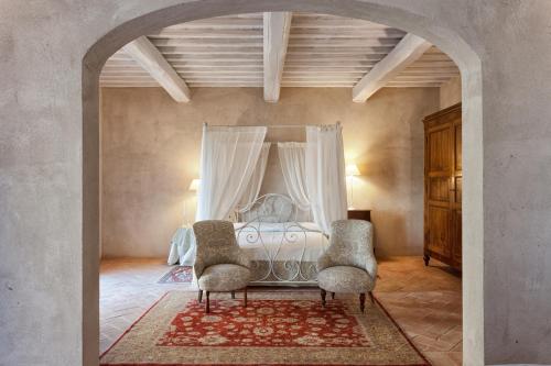 a bedroom with a bed with two chairs in it at Casanova di Neri Relais in Montalcino