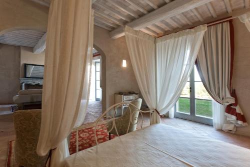 a bedroom with curtains and a bed and a window at Casanova di Neri Relais in Montalcino