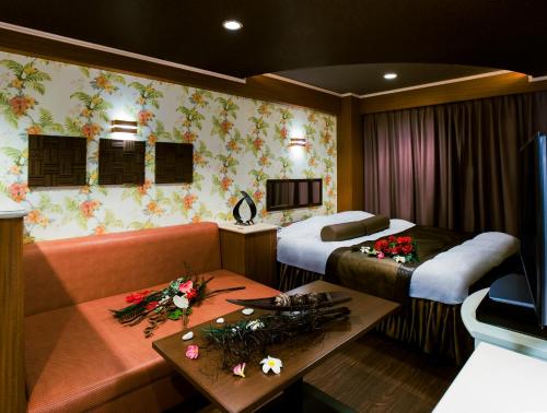 鹿児島市にある鹿児島 ココナッツリゾート マリーナ（レジャーホテル））のベッド2台とソファが備わるホテルルームです。