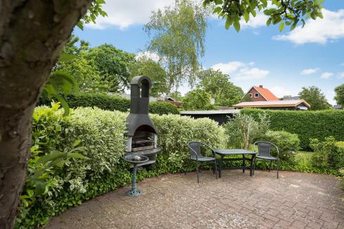 a patio with a grill and two chairs and a table at Kollund Rooms in Kollund Østerskov