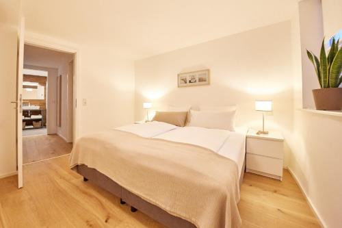 a white bedroom with a large bed and a plant at Zehn in Bernkastel-Kues