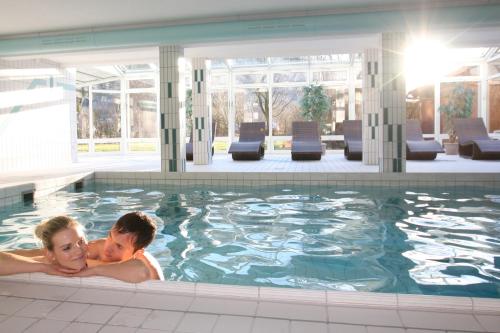 a man and woman laying in a swimming pool at Farbinger Hof in Bernau am Chiemsee