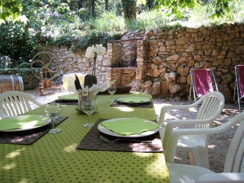 une table avec un tissu de table vert et des chaises blanches dans l'établissement Gite du Boulidou, à Cazilhac