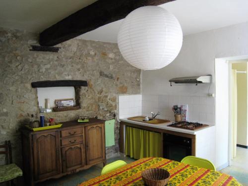 a kitchen with a table and a large light fixture at Gite du Boulidou in Cazilhac