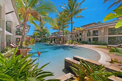 een groot zwembad met palmbomen en gebouwen bij 132 Temple Luxury Direct Studio in Port Douglas