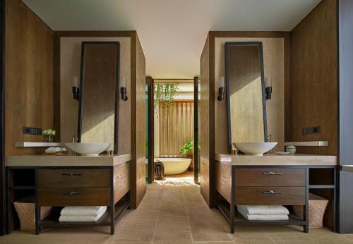 a bathroom with two sinks and two mirrors at Rosewood Phuket in Patong Beach