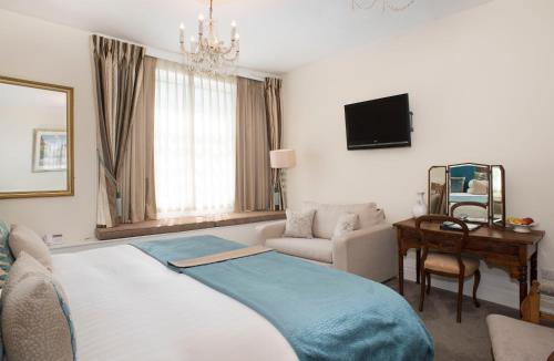 a bedroom with a bed and a couch and a mirror at Royal Seven Stars Hotel in Totnes