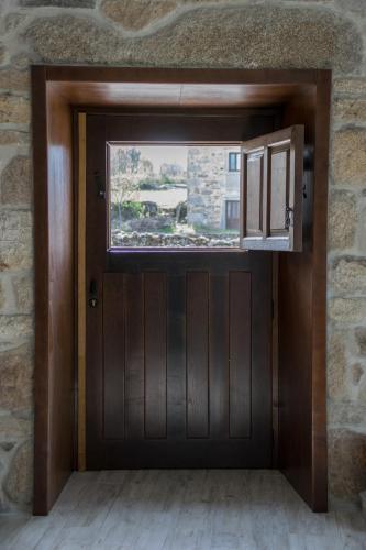 a wooden door with a window in a stone wall at Casa de Belharino in Miranda do Douro