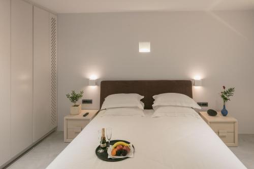 a white bed with a bowl of fruit on it at Aria Suites & Villas in Fira