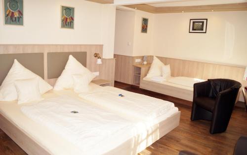 ein Schlafzimmer mit einem großen weißen Bett und einem Stuhl in der Unterkunft Hotel Gute Quelle in Beilstein