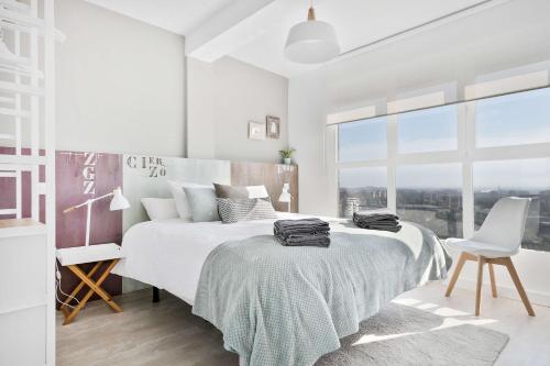 a white bedroom with a large bed and a chair at Mirador del Ebro in Zaragoza