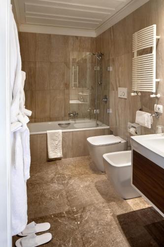 a bathroom with a tub and a toilet and a sink at Hotel Villa Belvedere in Taormina