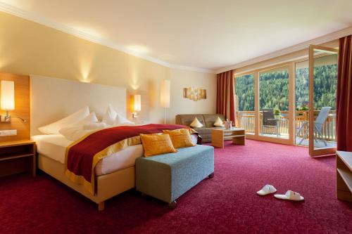 a hotel room with a bed and a balcony at Wohlfühl & Genusshotel Felsenhof in Bad Kleinkirchheim