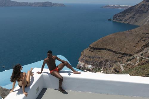 a man and a woman sitting on the edge of a boat at Aria Suites & Villas in Fira