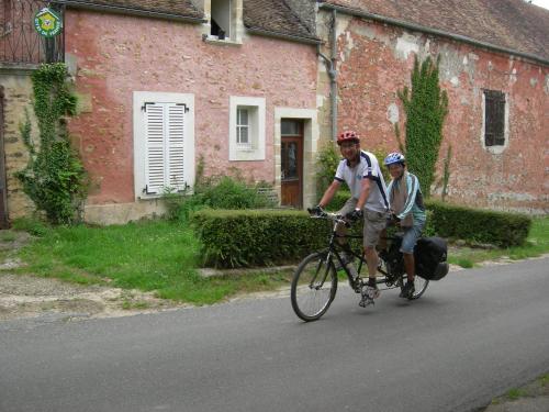 two men riding a bike down a street at La Ferme Rose in Cergy