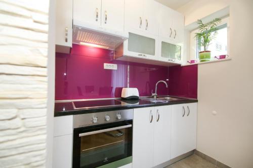 a kitchen with white cabinets and a purple wall at Apartment Anđelina, Split in Split