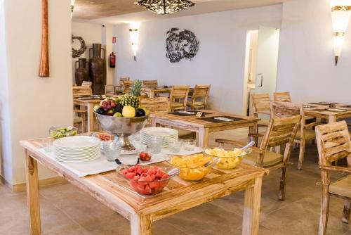 a table with bowls of fruit and plates on it at El Cortijo de Zahara by QHotels in Zahara de los Atunes