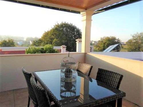 a glass table with chairs and a bird cage on a balcony at Casa Monte Alegre in Redinha