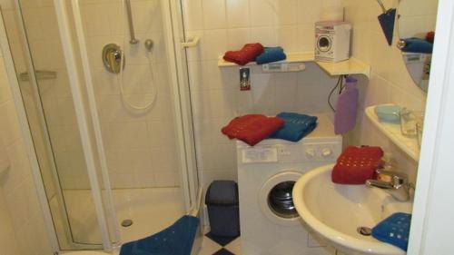 ein Badezimmer mit einer Dusche, einem Waschbecken und einer Waschmaschine in der Unterkunft Hafenblick-City Apartment Husum in Husum