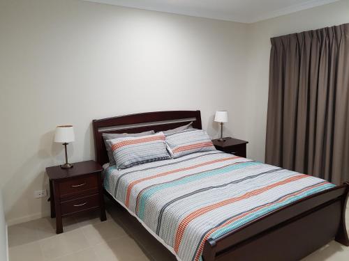 a bedroom with a bed with two night stands and two lamps at Jasper Place in Brisbane