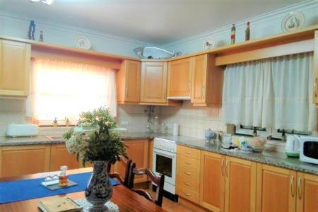 a kitchen with wooden cabinets and a table with a vase at Casa Monte Alegre in Redinha