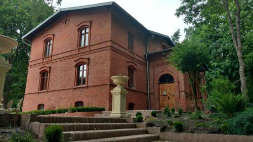 - un ancien bâtiment en briques rouges avec des escaliers devant dans l'établissement Dwór Mysinek, à Grabowiec