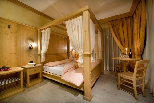 a bedroom with a canopy bed and a desk at Hotel La Tea in Livigno