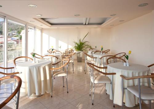 a row of tables and chairs in a room with windows at Viaros Hotel Apartments in Tolo