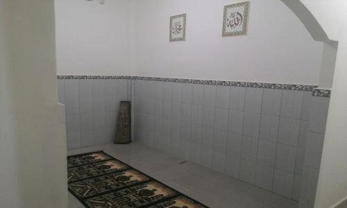 uma casa de banho com paredes em azulejos brancos e um tapete em Losmen Ibu Hj. Tarjo em Palimbão