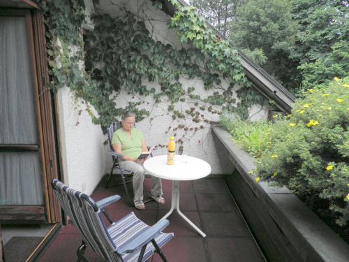 a woman sitting at a table on a patio at Gästehaus Sonneck in Bischofsgrün