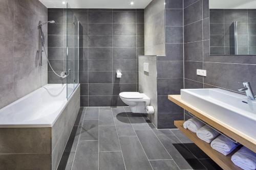 a bathroom with a sink and a toilet and a tub at Residenz Drachenstein Wildschönau in Niederau