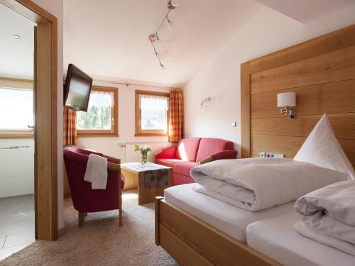 een slaapkamer met een bed, een stoel en een bank bij derWaldfrieden naturparkhotel in Herrenschwand