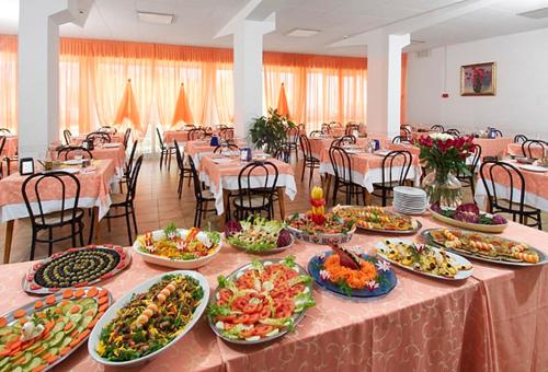 ein langer Tisch mit vielen Teller Essen drauf in der Unterkunft Hotel Dinarica in Marotta