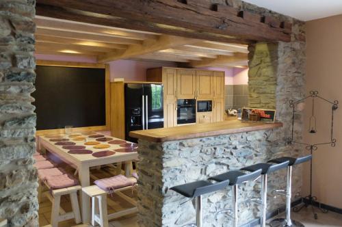 - une cuisine avec un mur en pierre, une table et des chaises dans l'établissement Gites "Aux Legendes d Ardenne", à Paliseul