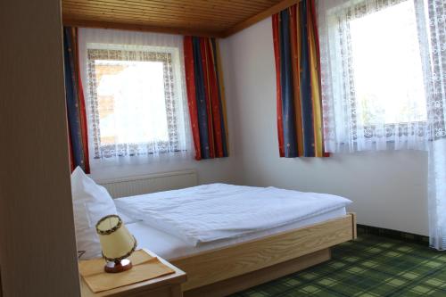 a small bedroom with a bed and two windows at Haus Aster in Wagrain